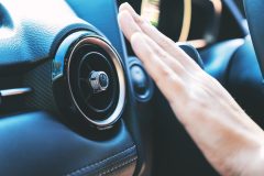 Closeup image of a hand checking the air conditioner system in the car
